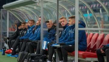 bewaehrungshilfe-besondere-umstaende Ersatzbank mit Spielern und Betreuern hinter Plexiglas im Fußballstadion