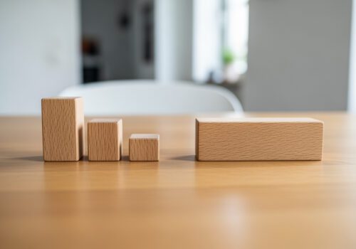 Symbolische Darstellung der Gesamtstrafenbildung: Drei einzelne Holzklötze sind größer als ein einzelner zusammengefasster Klotz.