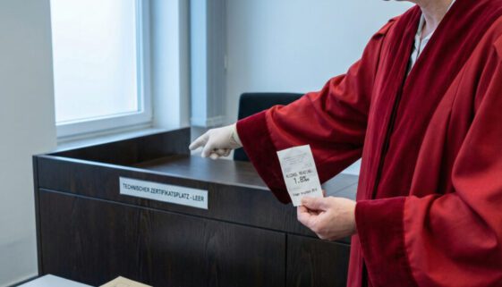 Ein Richter hält einen Beleg und zeigt entschieden auf den leeren Pultbereich, wo ein technisches Dokument fehlt.